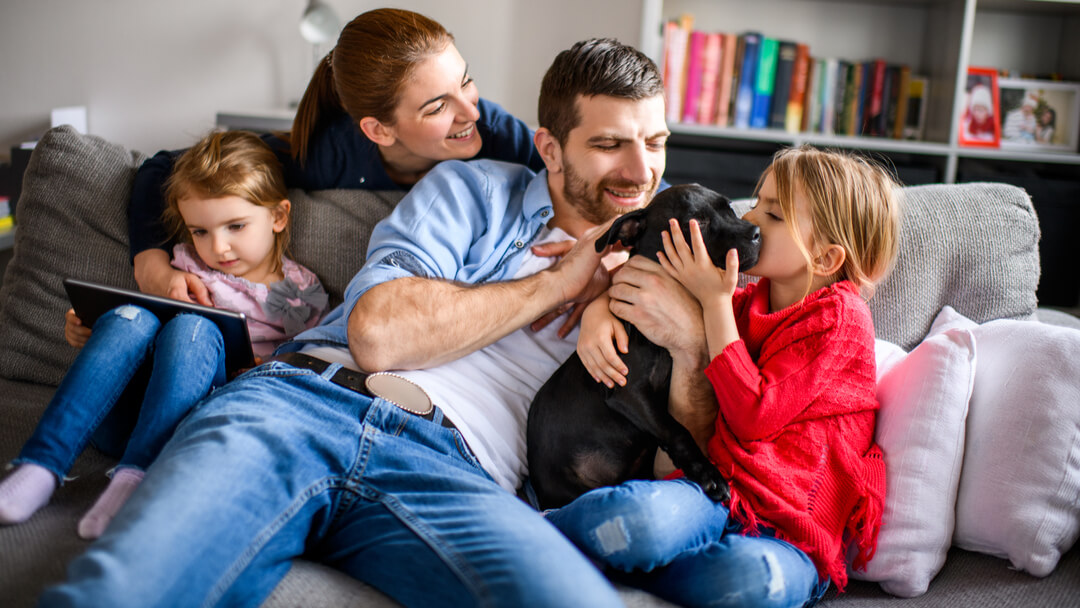 Family of four playing with black puppy