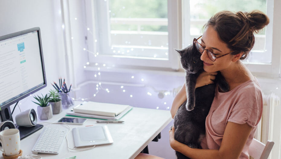 Woman cuddling cat in front of desktop
