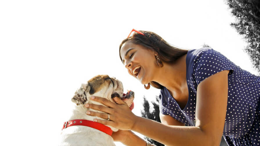 Woman holding her dog's head and smiling