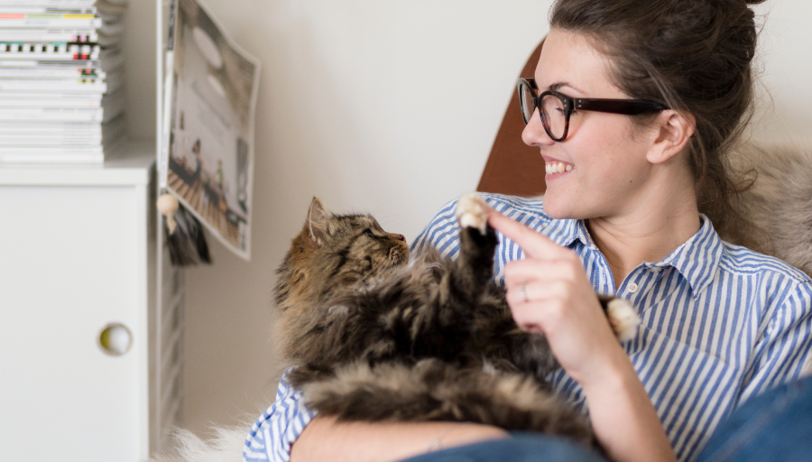 A woman sat with her cat in her lap touching it's paw with her finger