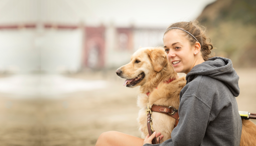 Woman sat outside with her dog on the lead next to her