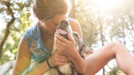 Young Woman cuddling her dog in the woods