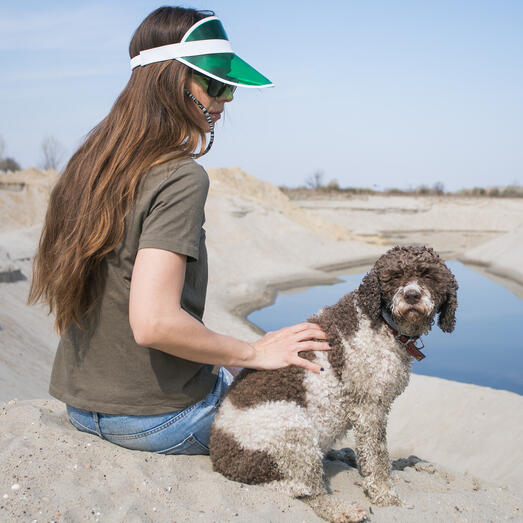 A girl sitting with Lagotto Romangnolo on the sand 