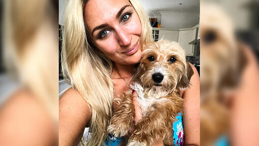 woman holding a long haired miniature dachshund