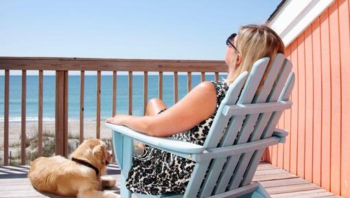 woman sitting on deck chair with dog by her side
