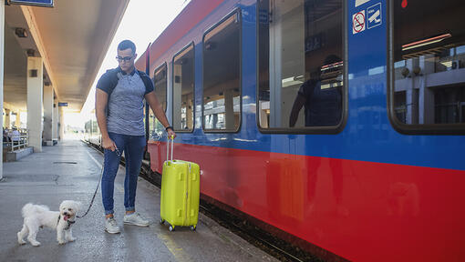 main getting onto train with pet dog