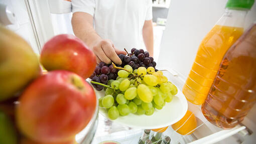 Man takes grapes from the refrigerator